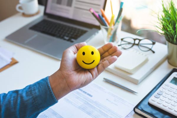 1. Salud Mental en el Trabajo; Un empleado en su escritorio, sonriente y relajado, cuidando de su salud mental en un ambiente laboral saludable gracias a Well Fair.